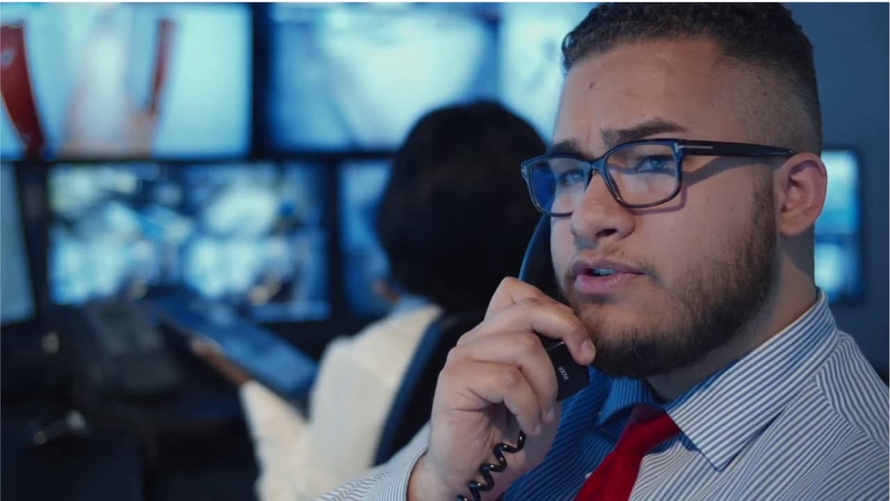 A guard in a command center on the phone