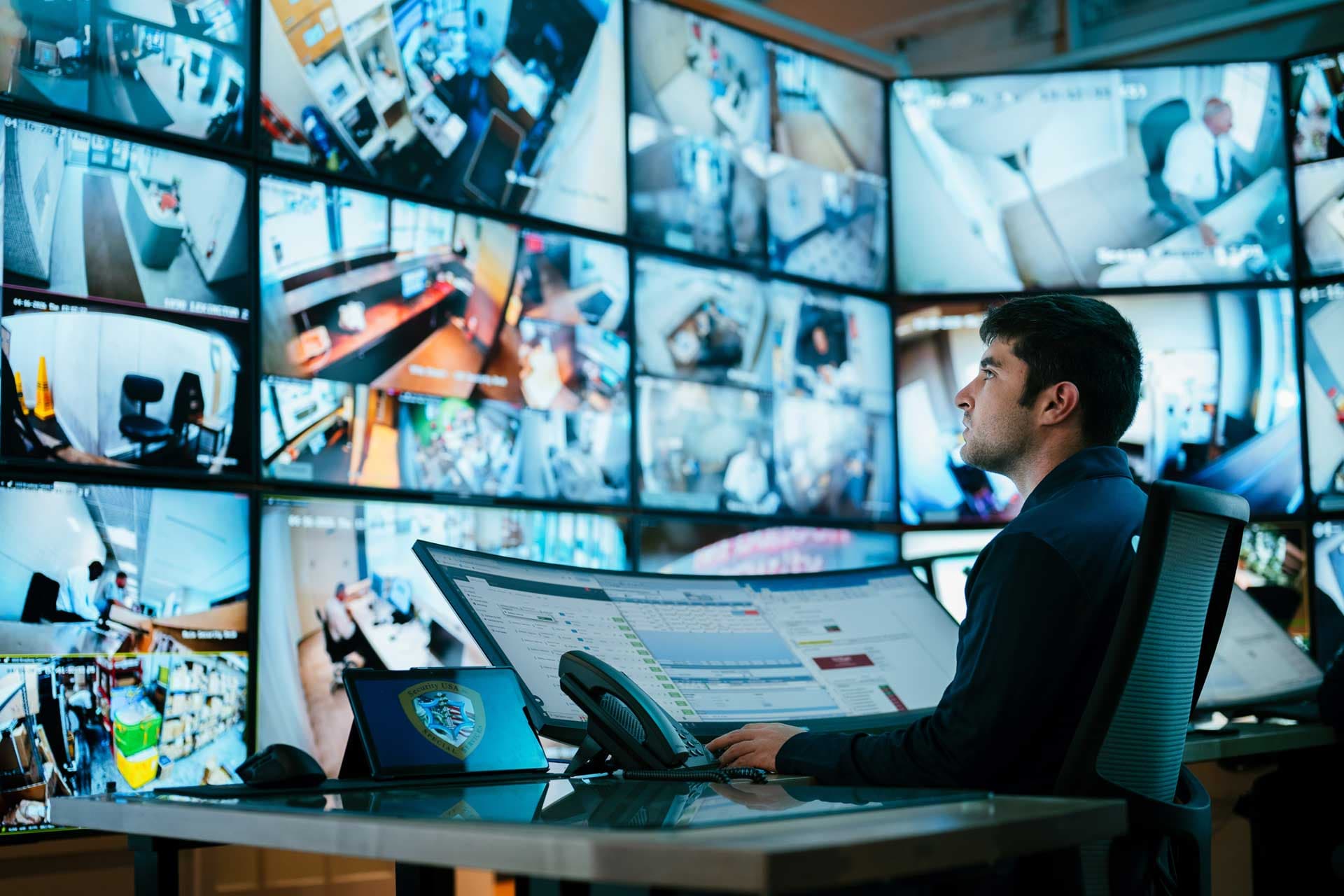 Image of data analyst analying security monitors in command center.