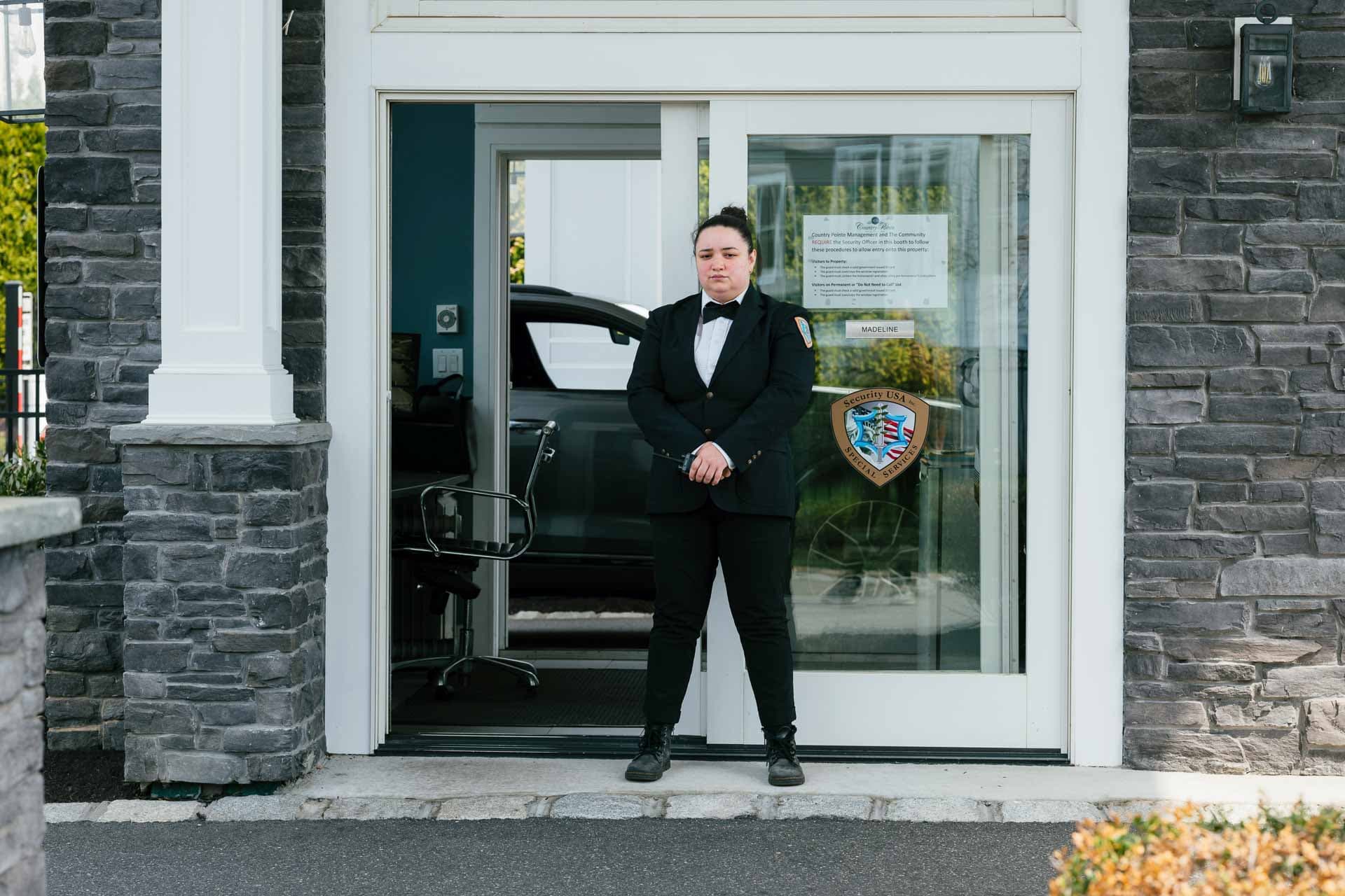 Image of a Security USA® gated community guard standing in front of front gate guard house.
