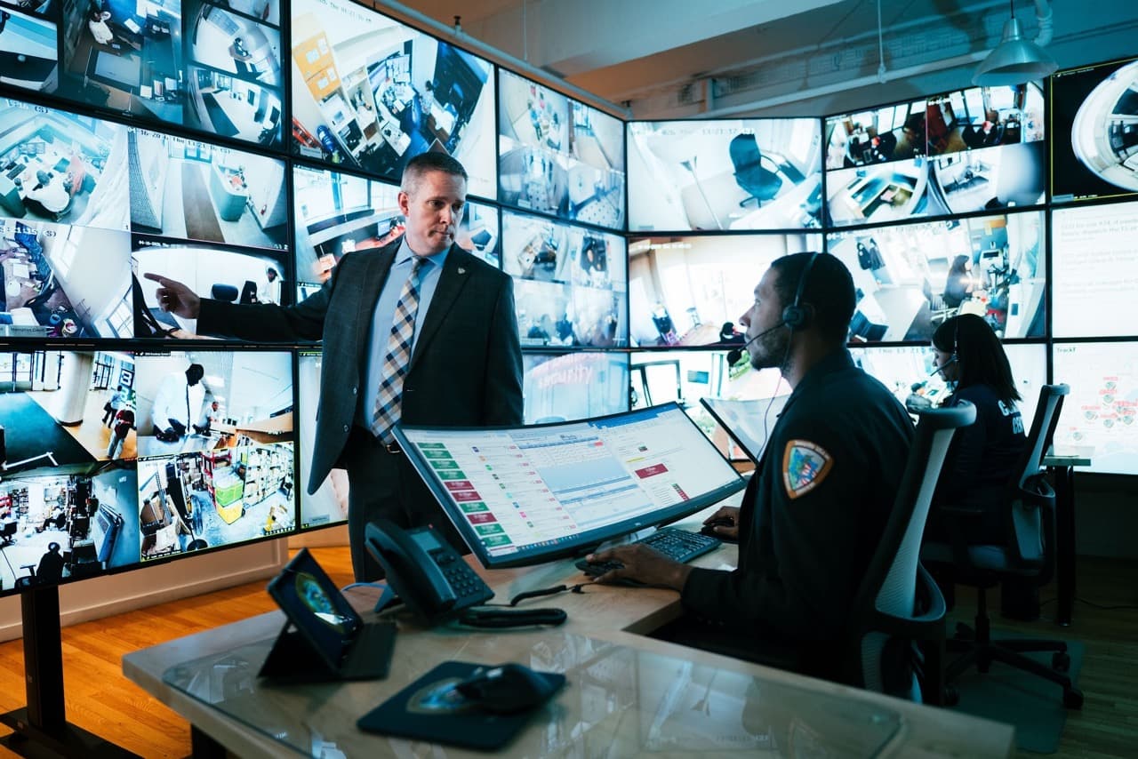 Image of security supervisor reviewing incident reports and live monitoring feeds with security personnel.