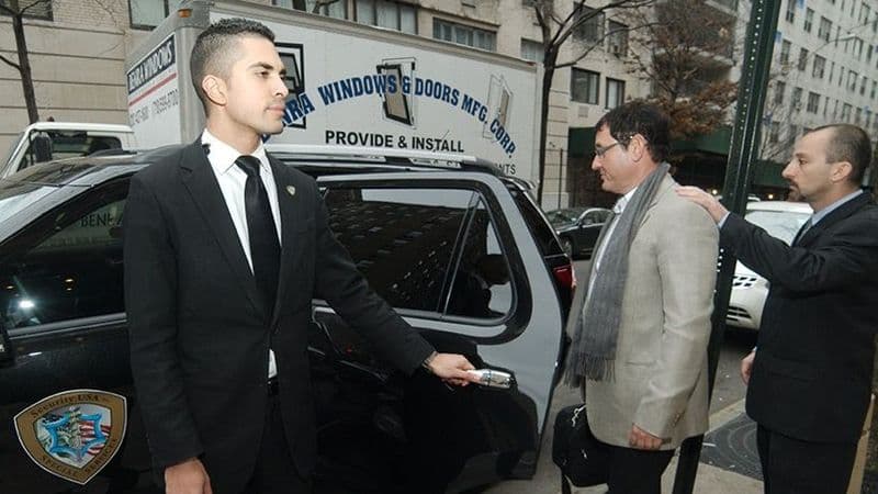 Image of a Security USA® armed executive protection agent holding a car door for an executive.