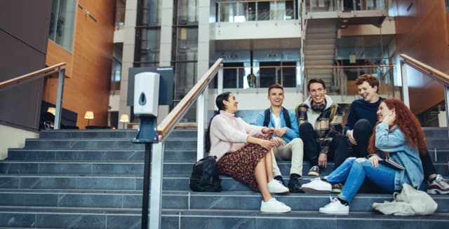 Image of kids sitting on the steps to a school.