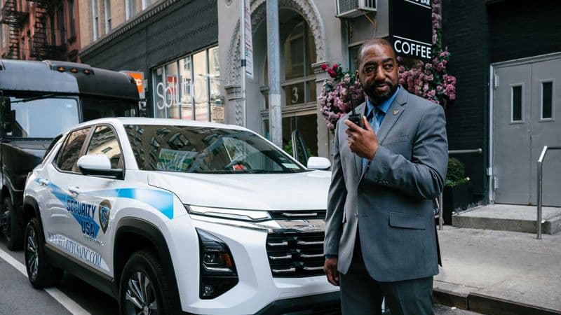 Image of security guard standing by Security USA® patrol car.