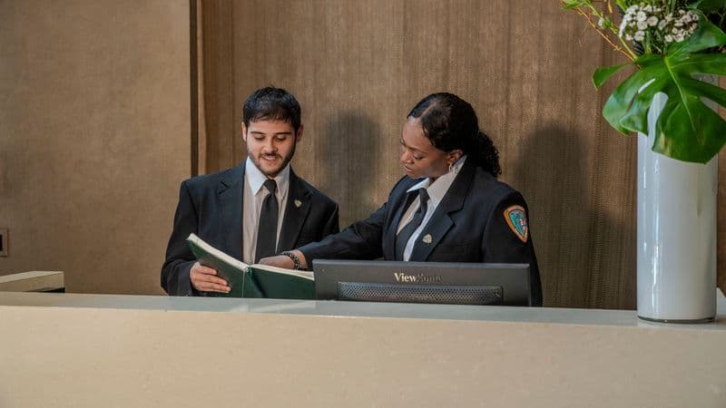 Image of two residential security guards behind a front desk.