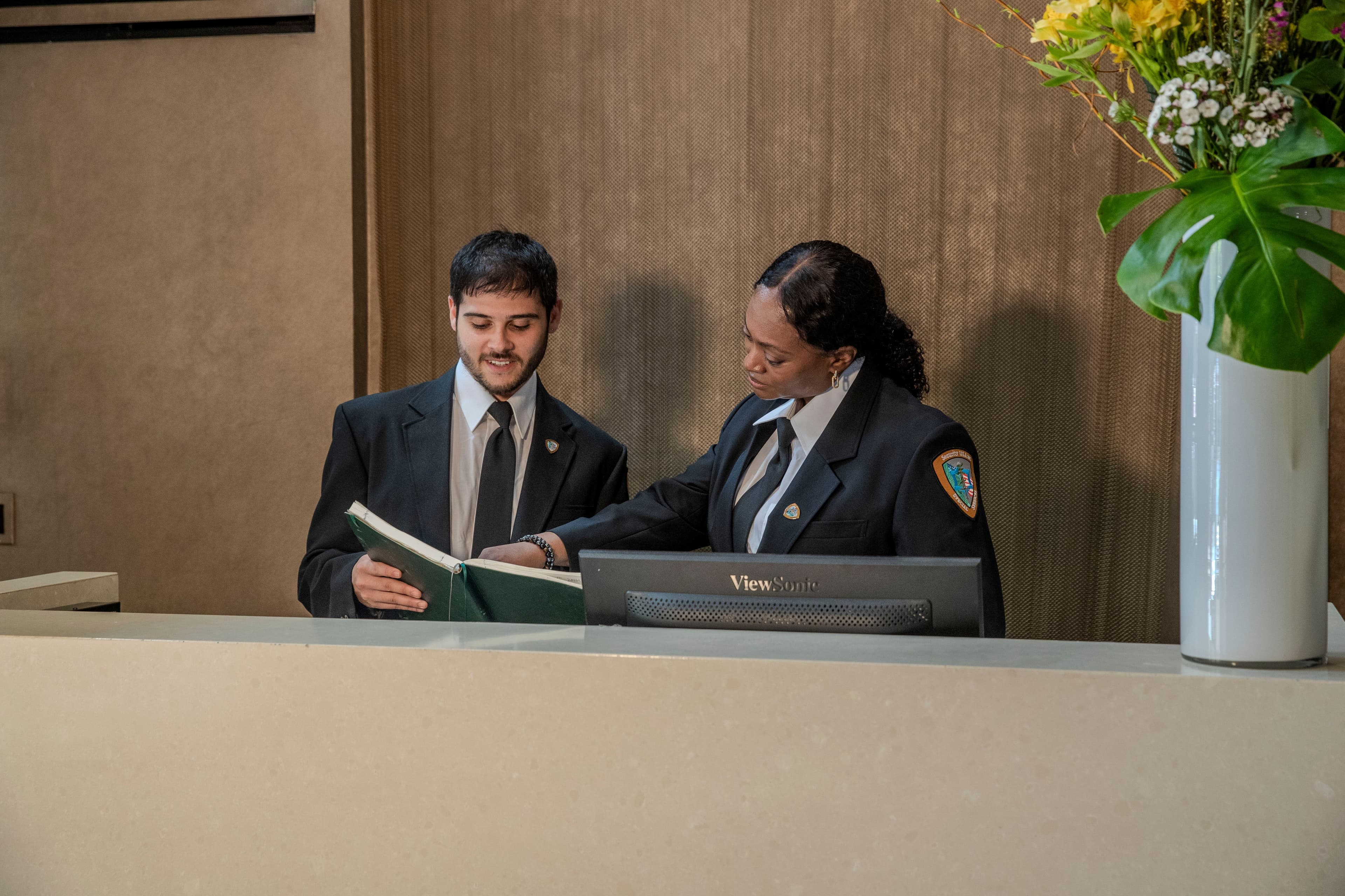 Image of two residential security guards behind a front desk.