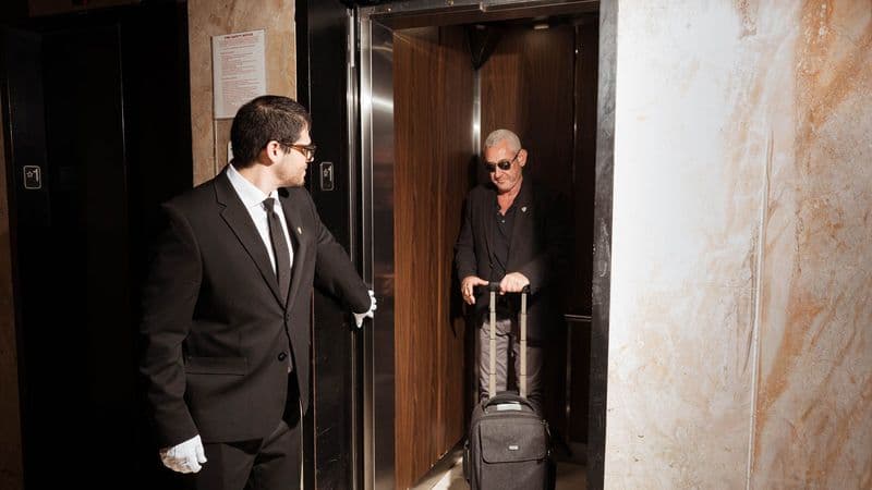 Image of a Security USA® white glove attendant assisting resident into elevator.