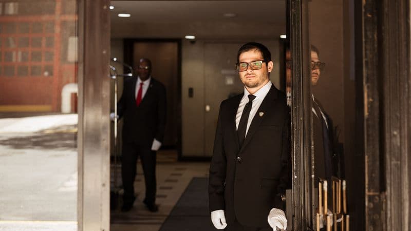 Security USA® white-glove attendant greeting a resident at a luxury building entrance